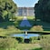 The Palace of Caserta with manicured gardens, a circular fountain and a paved walkway